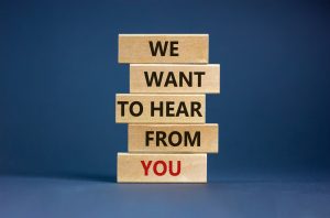 Wooden blocks with words ‘we want to hear from you’. Beautiful grey background. Copy space. Business concept.